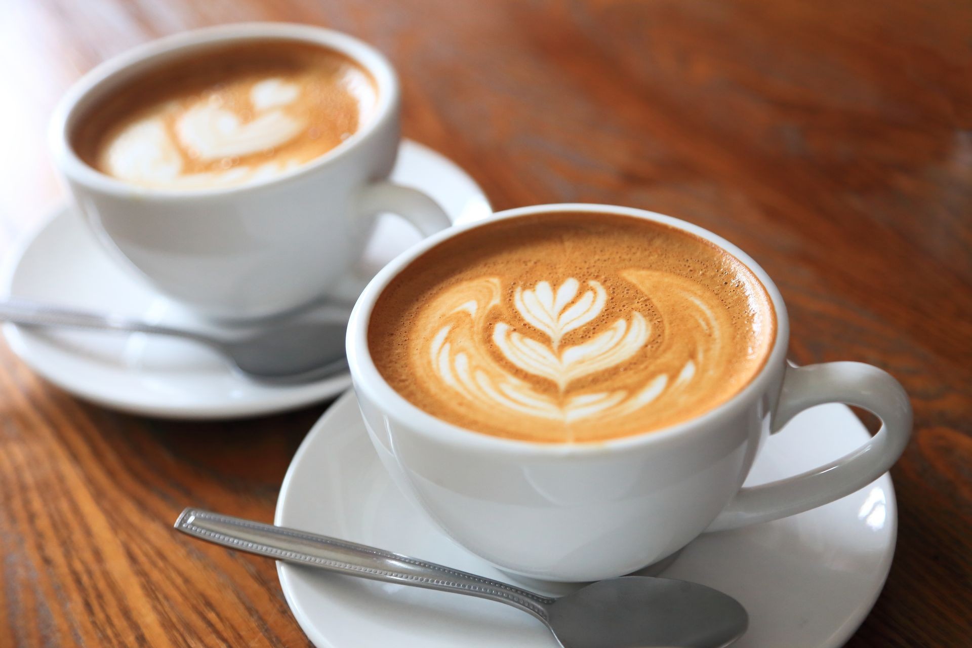 two cups of coffee latte art with tulip pattern on wooden table with copy space